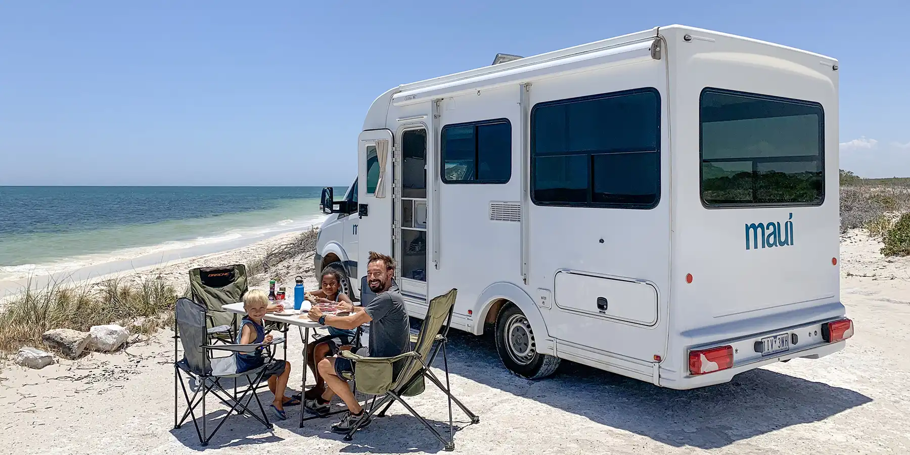 Father and kids having a picnic next to motorhome