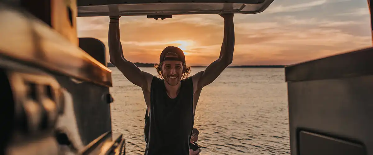 A man smiling while opening the boot of a campervan